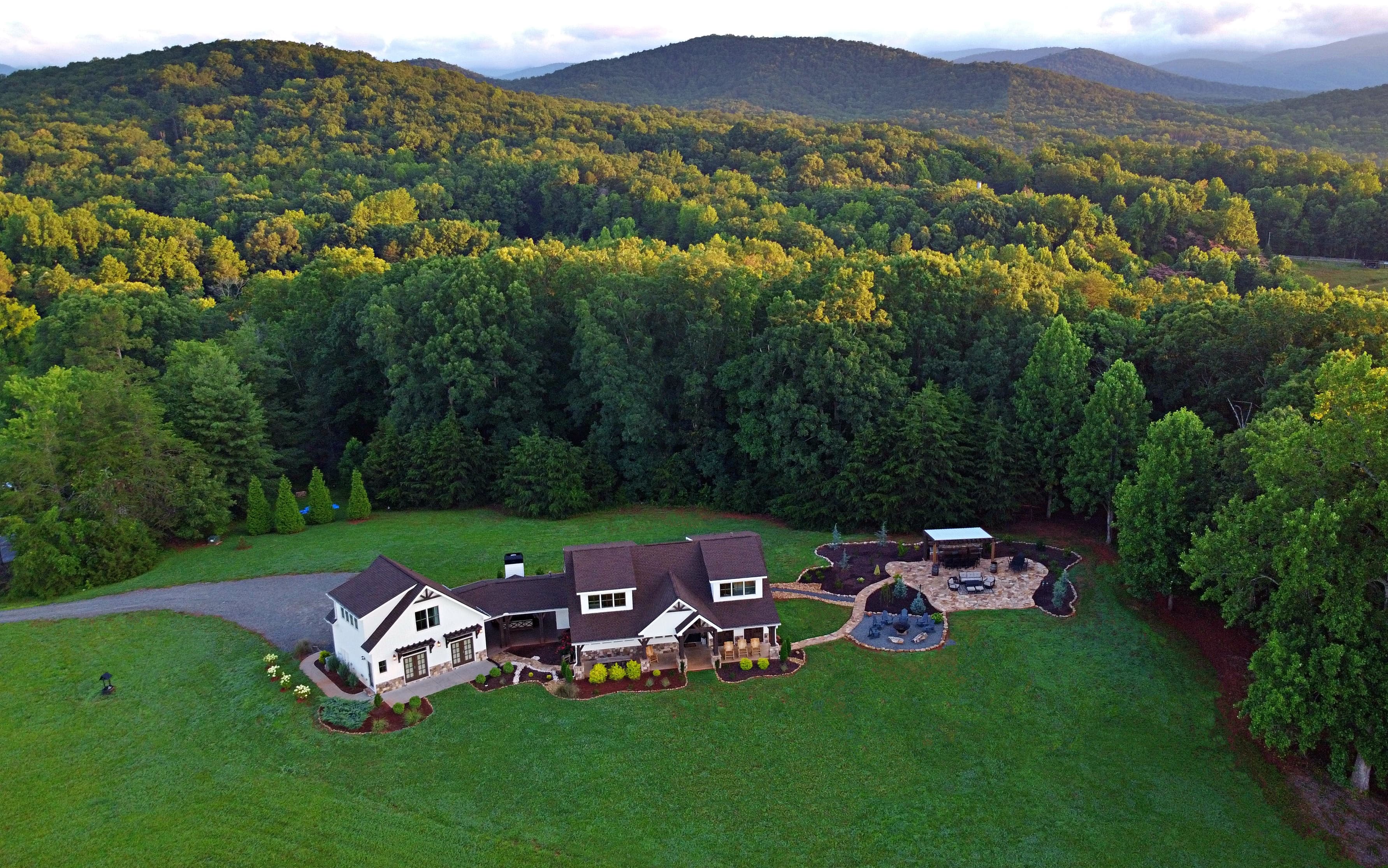 Drone view of white farmhouse with a main house and attached carriage house
