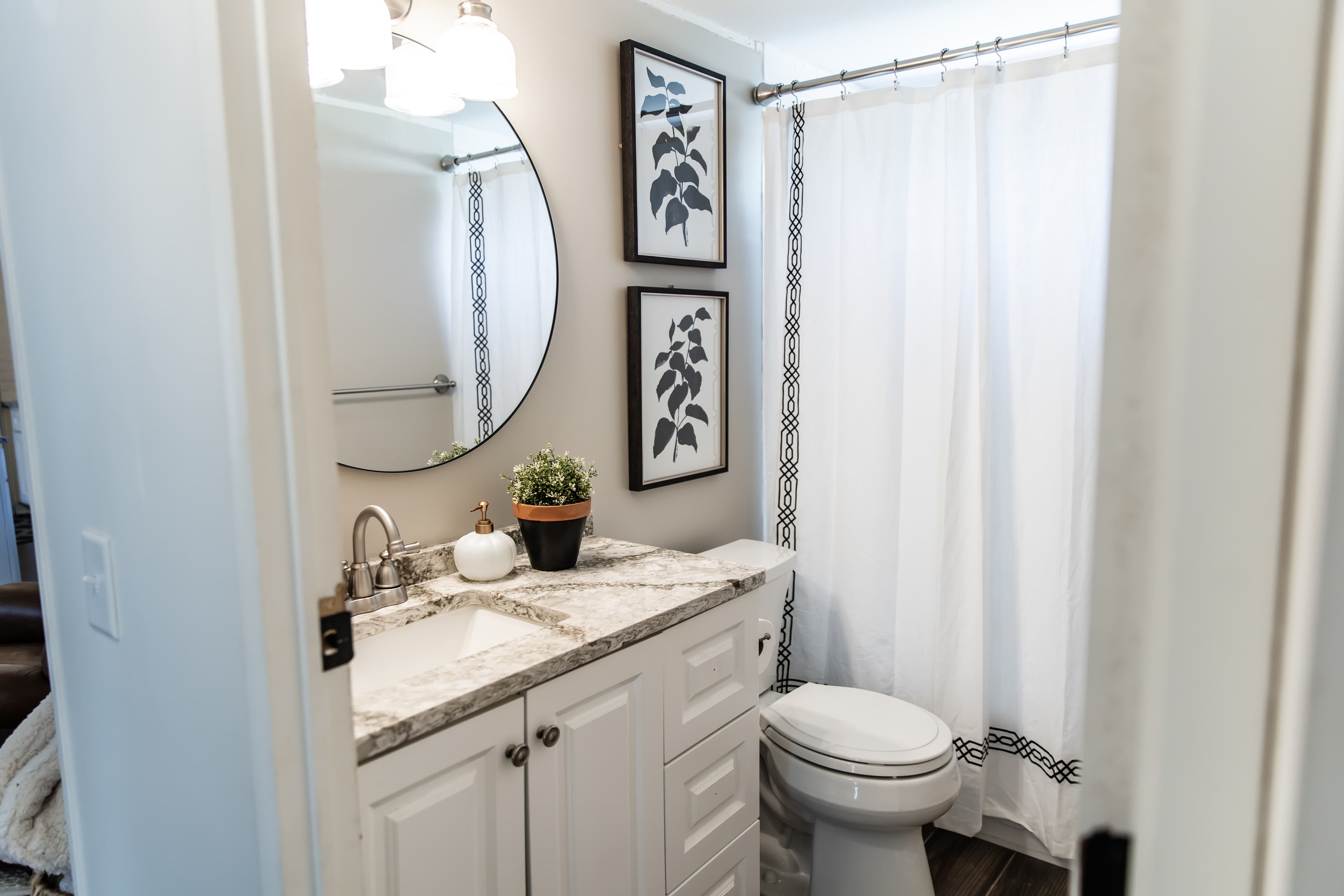 Bath 2 with white, tan and black decor and tub shower combo